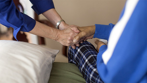 Hospice care worker holding patients hands